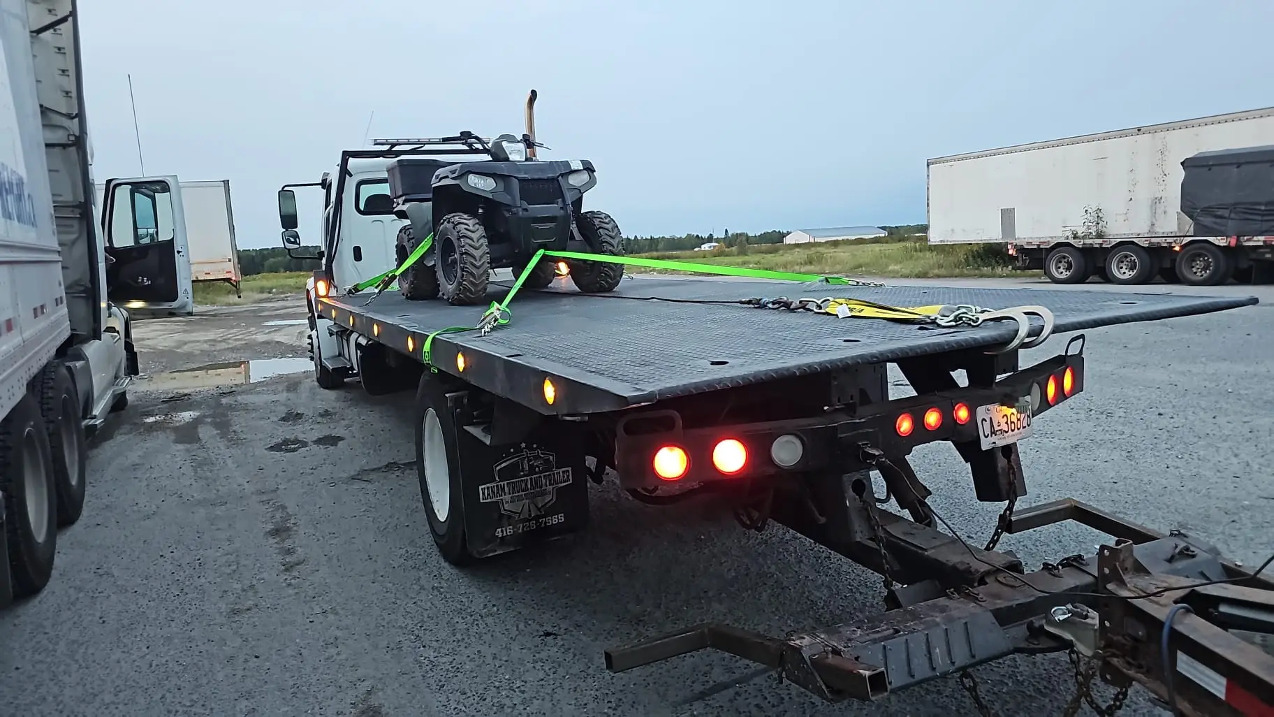 ATV strapped to the deck of a Total Towing flatbed truck