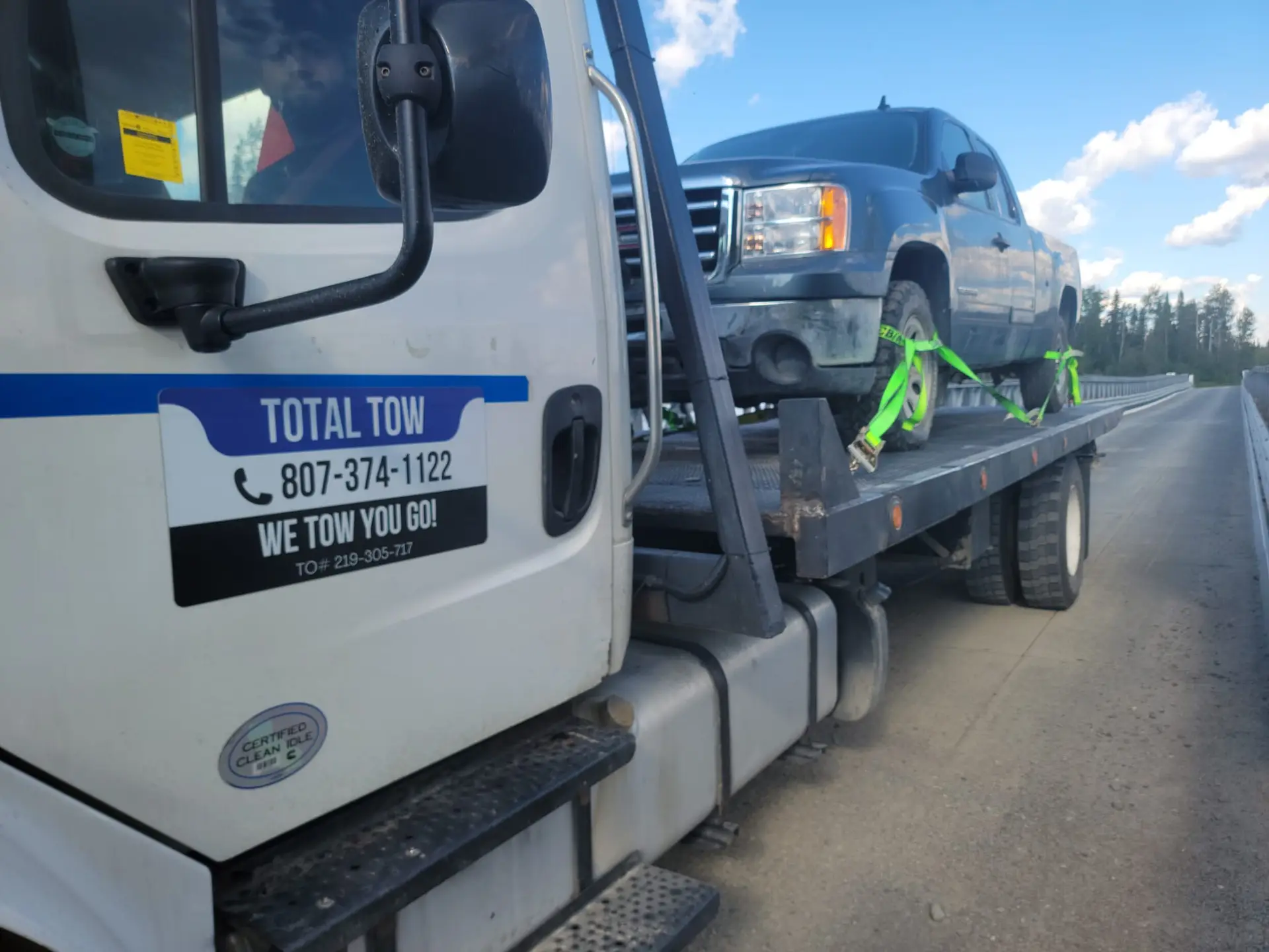 Total Towing flatbed tow truck with a pickup truck strapped on the deck in Thunder Bay