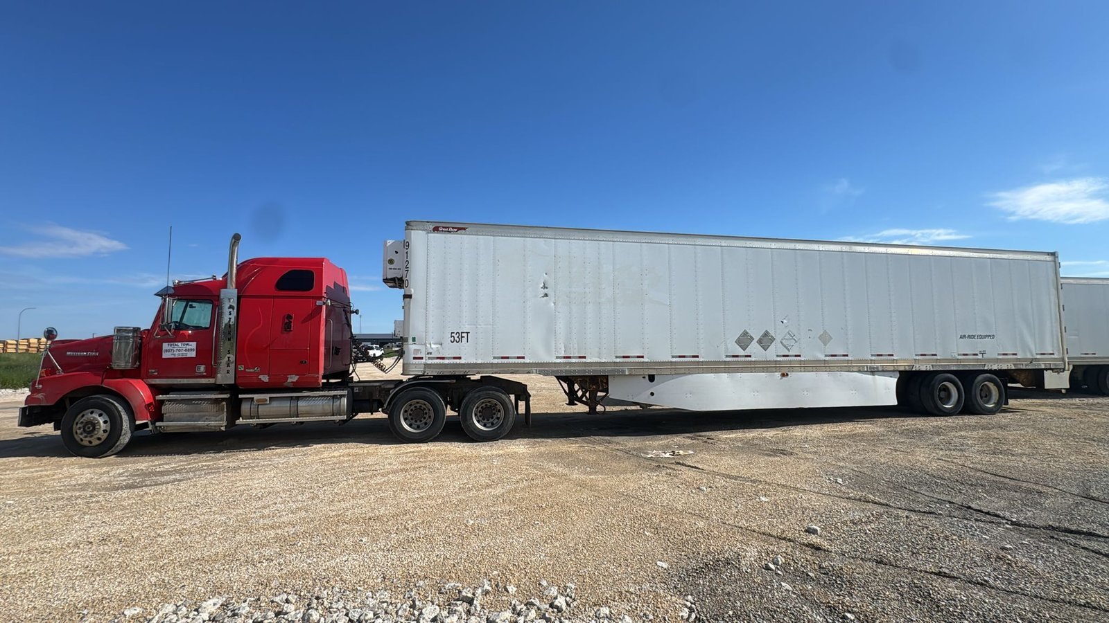 Red semi truck pulling a freight trailer across Northern Ontario