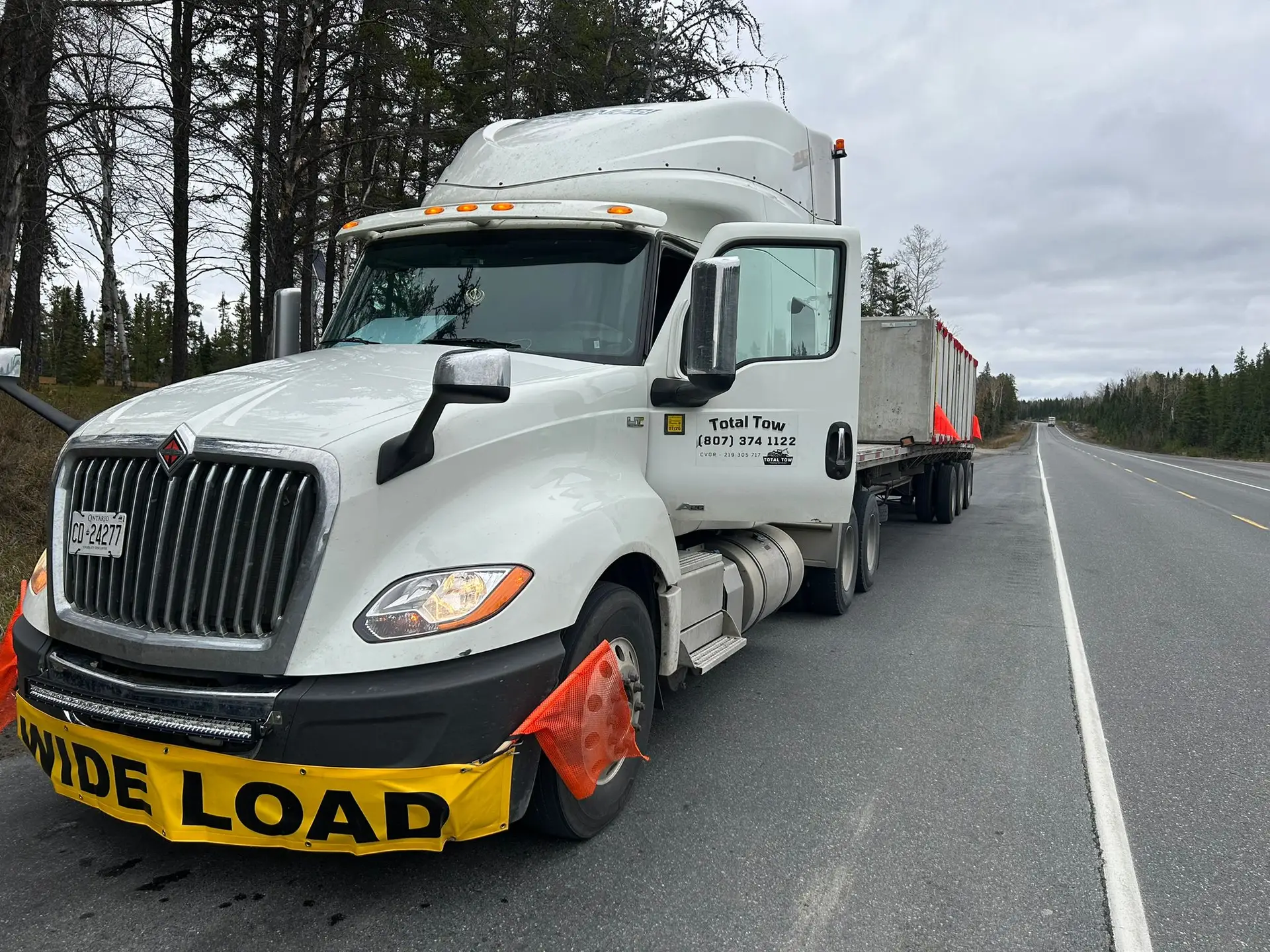 Total Towing semi truck with a wide load banner on a Northern Ontario highway