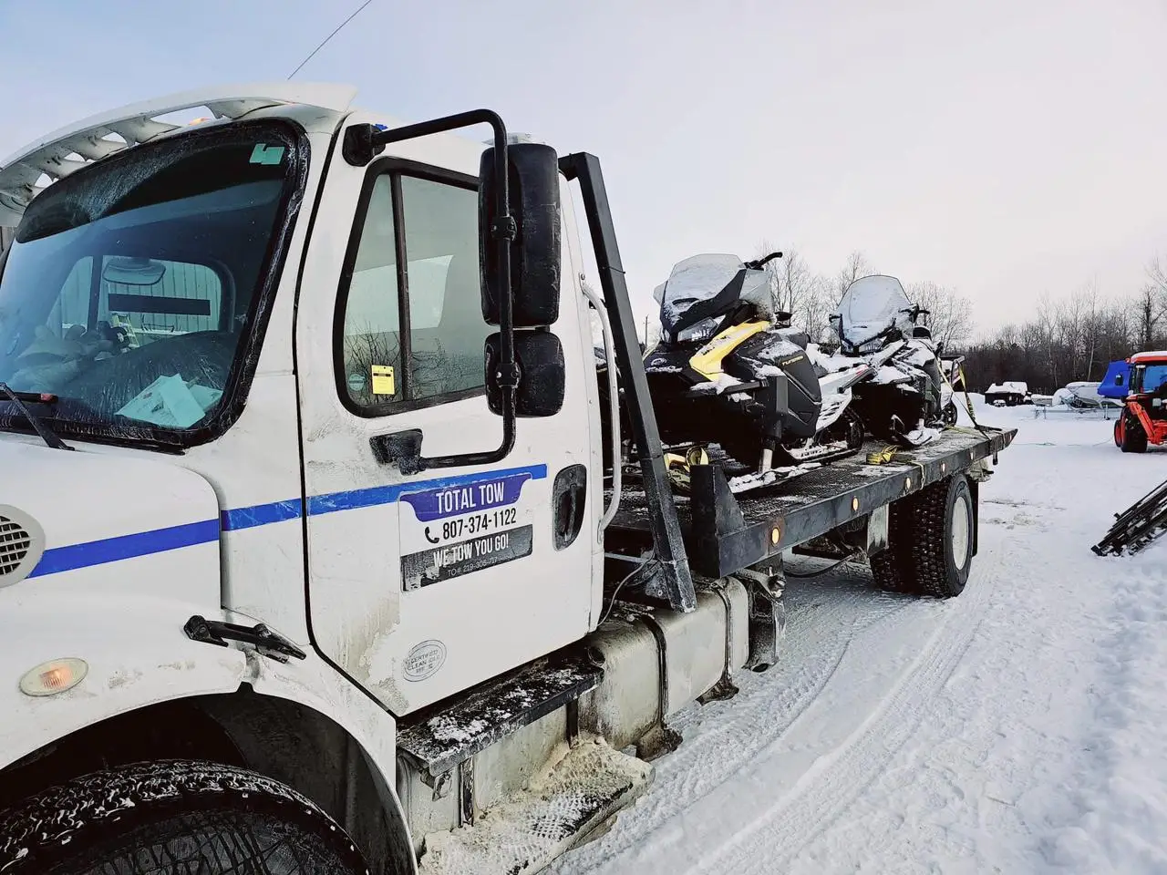 Total Towing flatbed hauling snowmobiles in winter near Thunder Bay